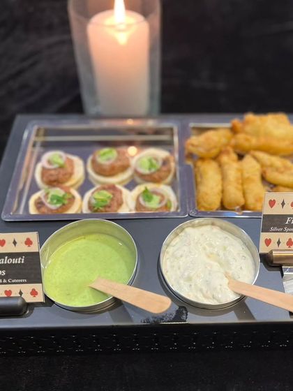 A platter of Mutton Galouti Kebabs and Fish Orley, perfect for a Diwali celebration. The card-themed labels and candle-lit presentation tie everything together for a festive cards night.