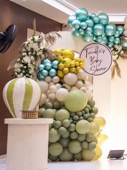 Details of the balloon decor, featuring a hot air balloon prop. I use a mix of balloon sizes and colors, like sage green and gold, to create an organic and visually interesting garland.