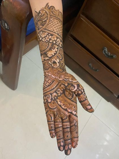 This full-arm bridal design is a testament to patience and detail. It features story elements like a palki and elephants, woven into the intricate patterns.