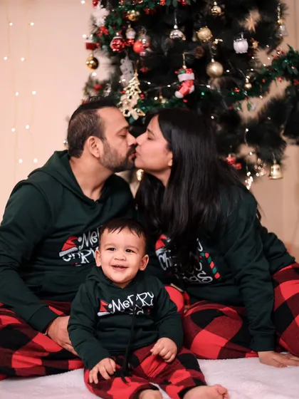 A sweet family Christmas portrait with matching pajamas and a kiss for the parents.