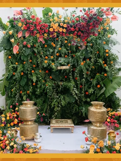 This vibrant Haldi ceremony backdrop is a celebration of color and tradition. I created a dense wall of fresh greenery and adorned it with a cascade of marigolds, fuchsias, and anthuriums, complemented by traditional brass pots for an authentic yet modern look.