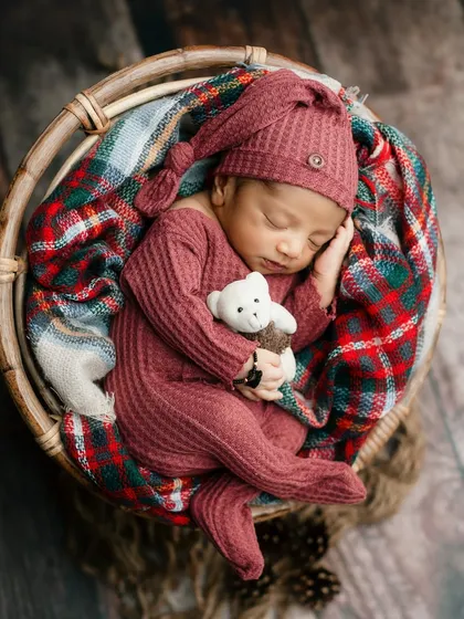 Cozy and warm in a rustic basket. The combination of a plaid blanket, a knitted outfit, and a sleepy pose creates a wonderfully rustic and comforting feel.