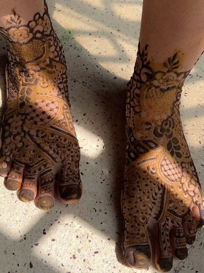 A still shot of the sunlit foot mehendi, showing the beautiful contrast between the dark henna paste and the skin.