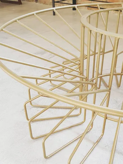A detail shot of the finished Bloom table base, showing the graceful curves and clean weld joints. The gold powder coating gives it a durable and luxurious finish.
