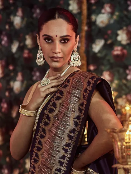The epitome of bridal grace. This image captures the intricate zari work on the pallu of a deep blue Banarasi silk saree, a classic choice for wedding ceremonies and receptions, paired with traditional pearl jewelry.