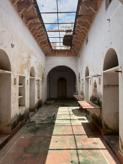 An interior corridor of the haveli before restoration, its potential hidden under layers of decay but visible in the elegant arches and niches.