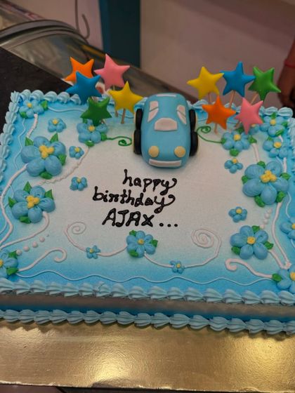 A custom car-themed cake with a cute blue fondant car and colorful star toppers. This design is perfect for a young child who loves cars and bright colors.
