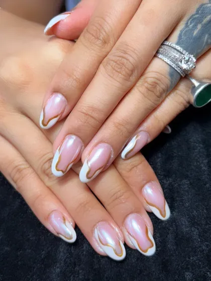 A closer look at the abstract gold and white French tip design, showing the beautiful, fluid lines.