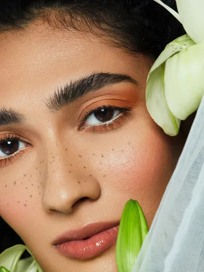 A fresh, natural look with faux freckles, a pop of orange eyeshadow, and a subtle white liner to brighten the eyes.