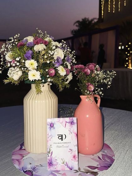 A charming table centerpiece for a Haldi carnival, with fresh flowers in pastel vases and a custom menu card.