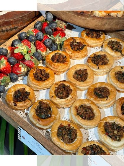 A wooden tray of our savoury mushroom vol-au-vents, served alongside fresh strawberries and blueberries. A perfect combination of flaky pastry and creamy filling.
