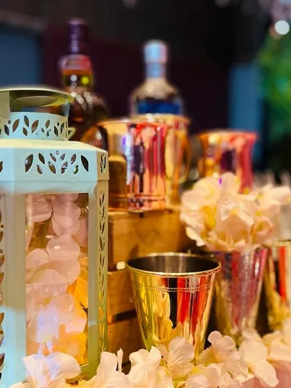 Soft, ambient lighting and delicate details. This image captures the mood with soft-focus lights on decorative lanterns and metallic glassware, accented with delicate white flowers for a touch of classic elegance.