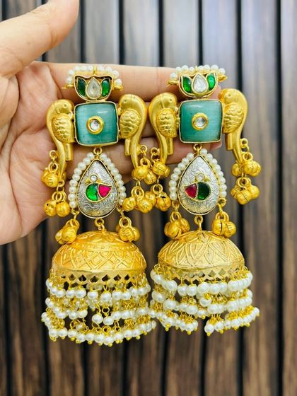 Statement earrings featuring a parrot motif in gold, with green stones and layered jhumka drops. These are a playful yet traditional accessory.