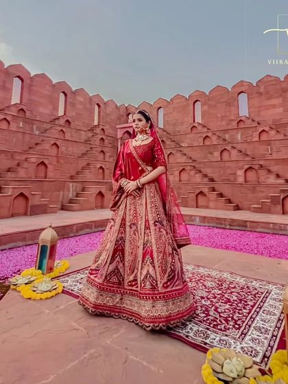 This classic red bridal lehenga is a masterpiece. The intricate paisley and floral embroidery create a rich texture, perfect for a traditional wedding ceremony.