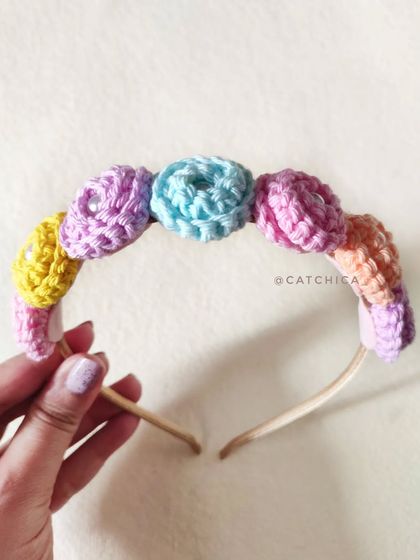 Holding up our pastel floral crochet tiara. The craftsmanship is delicate, and it's designed to be lightweight and comfortable.