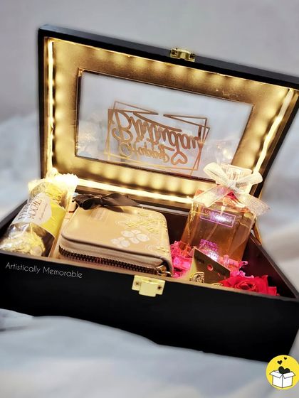 A birthday hamper curated with a wallet, perfume, and Ferrero Rocher chocolates, all glowing under the light-up lid.