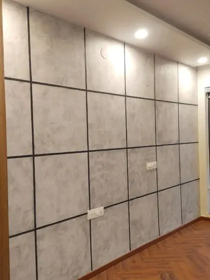An industrial-style accent wall with a concrete texture finish, sectioned into large panels with clean black lines to create a sophisticated, modern look in a bedroom.
