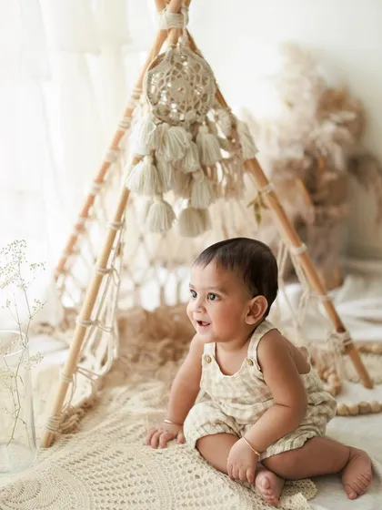 Cuteness overload at this one-year-old's photo session. The natural, boho-themed setup with a macrame teepee is a popular choice for first birthday shoots.