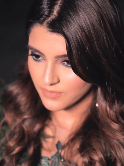 A close-up portrait of a bride with a soft, romantic makeup look. The focus is on her expressive eyes and the gentle waves of her hair.