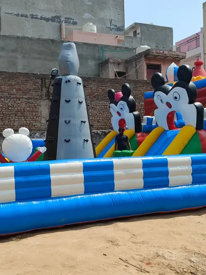 A side view of the Mickey-themed "Fun City" bouncy, showing the inflatable climbing tower and multiple character figures that decorate the structure.