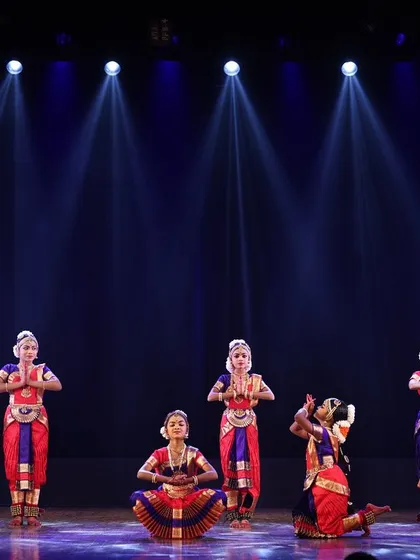 A large group of my students on stage, their synchronized poses and vibrant costumes creating a stunning visual spectacle under the professional stage lighting.