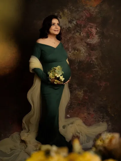 A dreamy, painterly portrait. The warm, out-of-focus elements in the foreground add depth and an artistic touch to this beautiful shot of a mother-to-be.