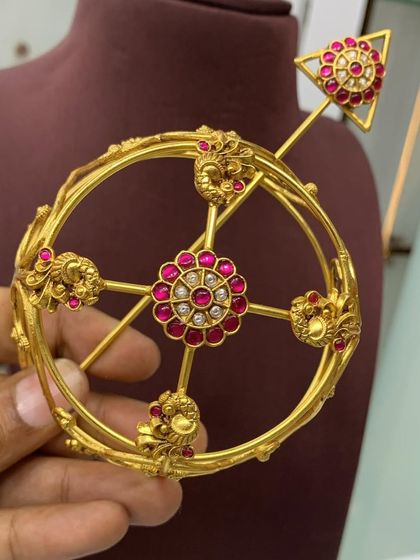 This angle shows the top view of the red stone bun cover, with its central floral motif and surrounding peacock designs. A beautiful piece for any bride.