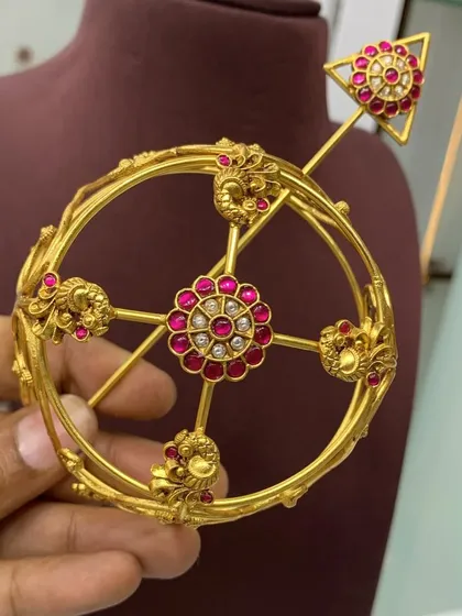 This angle shows the top view of the red stone bun cover, with its central floral motif and surrounding peacock designs. A beautiful piece for any bride.