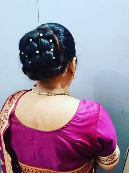A neatly woven braided bun decorated with pearl pins. This is a durable and elegant hairstyle suitable for long hours of celebration.