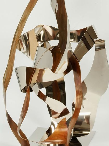 A detail of the "Drunken DNA" piece, showing the interwoven bands of reflective steel and matte bronze.