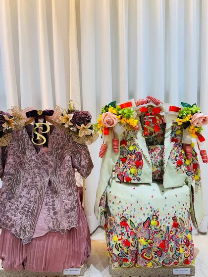 A beautiful contrast of styles. The groom's mauve, intricately embroidered outfit stands beside the bride's vibrant, multi-colored ensemble, both styled to perfection.