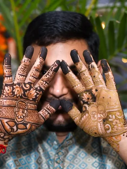 An artistic close-up of a groom's hands, showcasing the intricate details of his mehendi design. We focus on capturing both the grand moments and the fine details of your pre-wedding ceremonies.