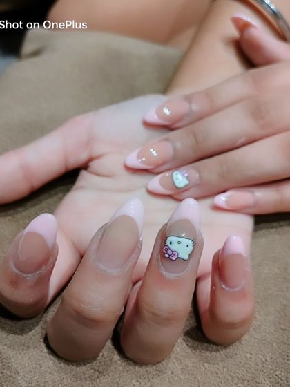 Another view of the Hello Kitty nail art, showing the character charm on long, almond-shaped nails with a light pink French tip.