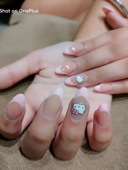 Another view of the Hello Kitty nail art, showing the character charm on long, almond-shaped nails with a light pink French tip.