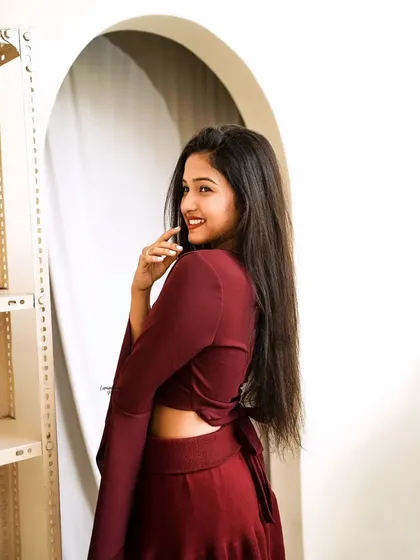 A happy, over-the-shoulder glance, showcasing the back tie-detail of the maroon crop top.