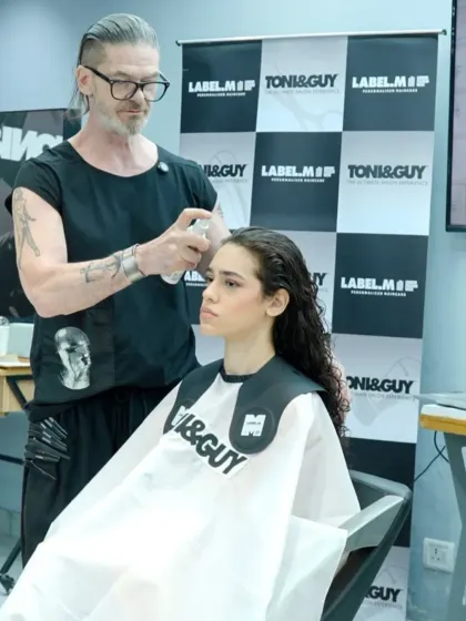 Using professional tools for a flawless finish. Bill Watson applies Label.M product to a model's hair, demonstrating how to use styling products effectively to achieve a desired texture and hold.
