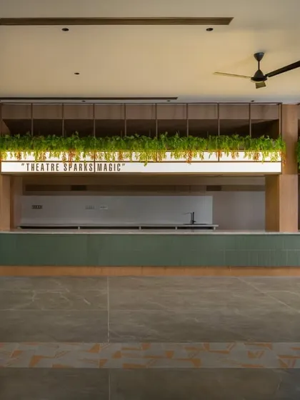 The lobby of the Sri Kumaran School auditorium is designed as a welcoming space for art and culture. We used warm wood paneling, lush greenery, and a prominent light feature to create an inviting atmosphere that encourages guests to linger and connect before a performance.
