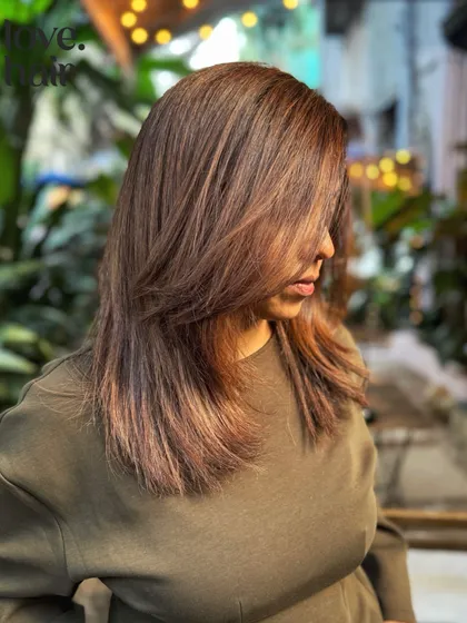 A side profile showing how the light hits this mahogany balayage. The layers and color work together to create a dynamic and face-framing effect.