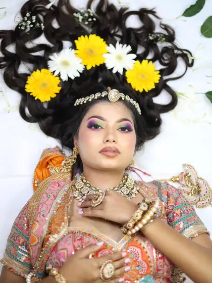 A bright and beautiful portrait with colorful makeup that complements the floral theme. The skin is kept fresh and dewy, perfect for a daytime event like a Haldi or Mehendi.