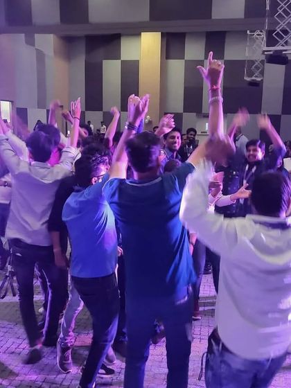 The employees of ITC Infotech with their hands in the air, fully immersed in the live music experience.