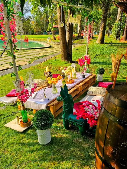A vibrant and colorful daytime picnic by the pool. This setup uses a low pallet table with bright cushions and floral arrangements, creating a cheerful and relaxed atmosphere for a sunny celebration.