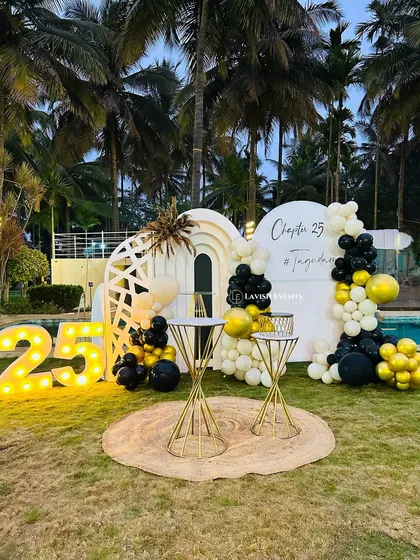 Celebrating "Chapter 25" with a chic outdoor setup featuring marquee numbers and a black and gold theme.