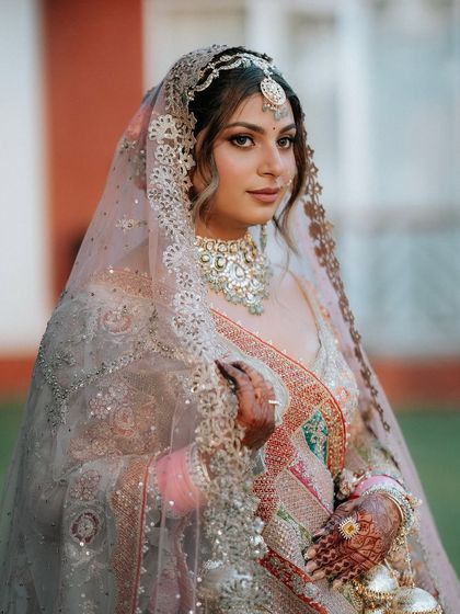 A close-up of Khyati under her veil. Her makeup is defined and glamorous, with a perfect winged liner and soft, glowing skin.