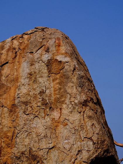 Sometimes you just have to take a moment to read the rock. This photo shows a climber contemplating her next move against the vast, beautiful backdrop of Hampi's boulder fields.