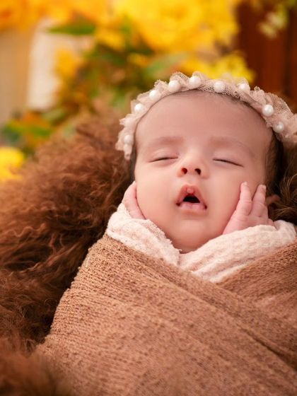 A detailed close-up of a sleeping newborn's face, with tiny hands resting on their cheeks. We focus on capturing these innocent, fleeting expressions and poses that you will cherish for years to come.
