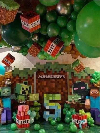 We built a complete Minecraft world for this 5th birthday party. The decoration includes a pixelated backdrop, character cutouts like Steve and Creepers, TNT block props, and a ceiling full of green balloons.