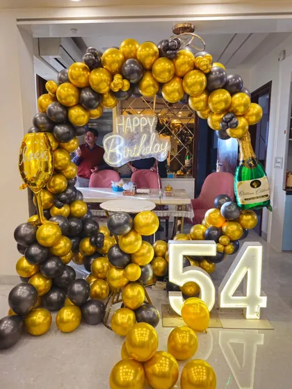 A clear photo of the black and gold 54th birthday setup, showing the reflective quality of the chrome balloons.