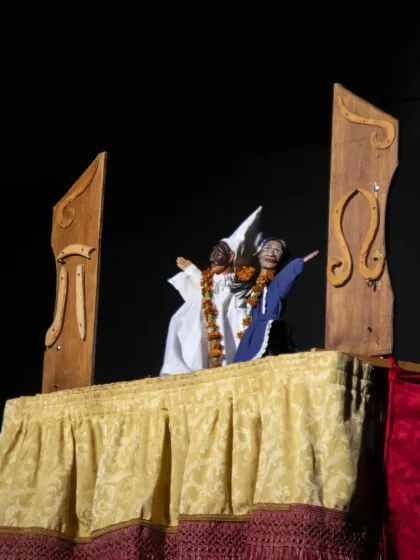 Two characters from 'Io, Pulcinella' interact on their traditional Italian puppet stage. The show is a playful homage to Neapolitan culture and four centuries of puppetry tradition.