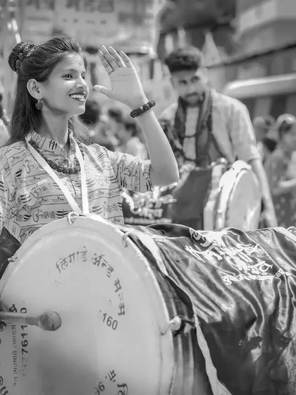 The black and white version of the smiling dhol player, capturing her infectious happiness and the spirit of the festival.