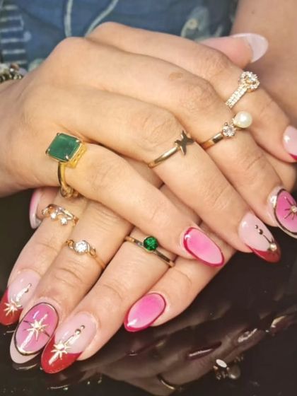 A full view of the playful pink and red manicure with gold starbursts and rhinestone embellishments.